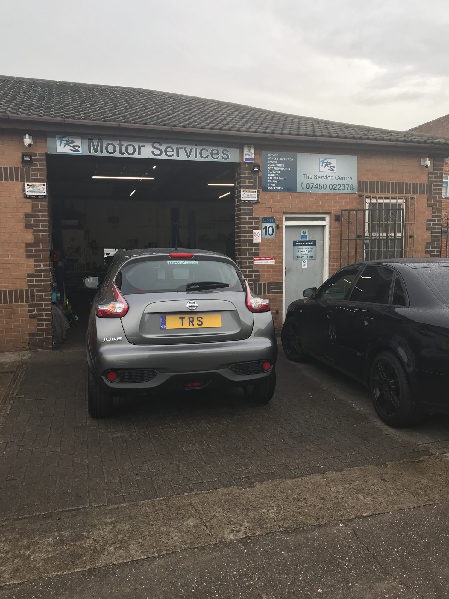 A grey Nissan Juke with a TRS number plate outside the open workshop bay