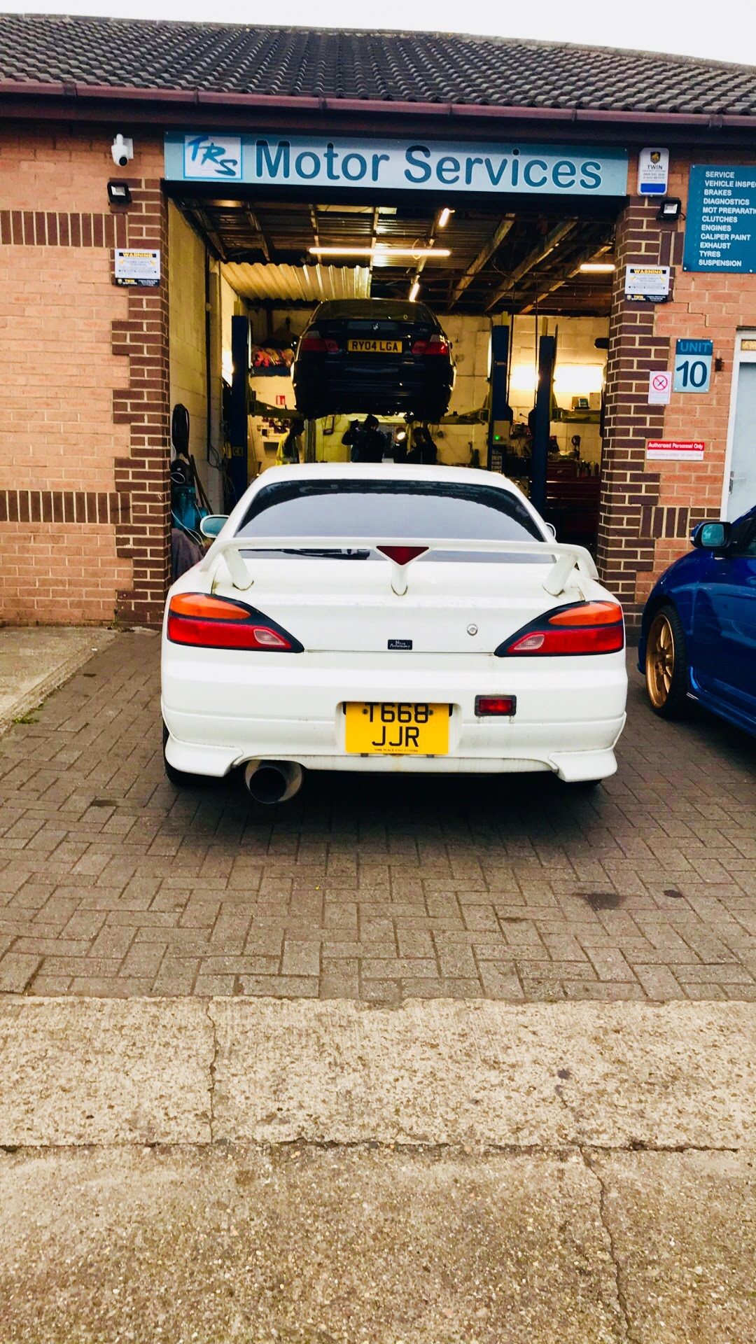 A white Nissan Silvia parked in front of the open bay
